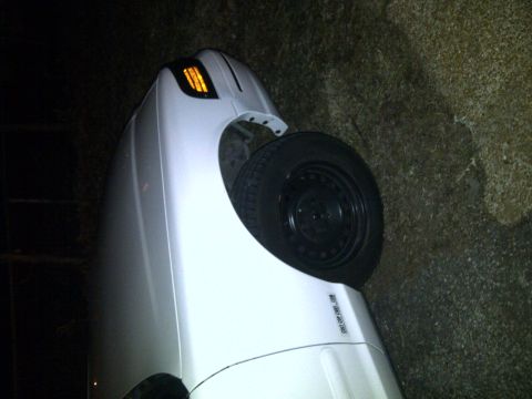 2000 Ford Crown Victoria - A white vehicle has overturned and is resting on its side, showing the passenger side exterior.