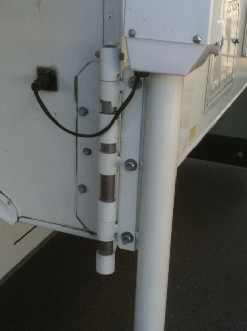 1986 Yugo GV - Close-up view of a white camper door hinge and latch assembly.