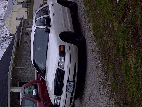 2000 Ford Crown Victoria - A white 2000 Ford Crown Victoria is parked next to a red pickup truck on a gravel driveway.
