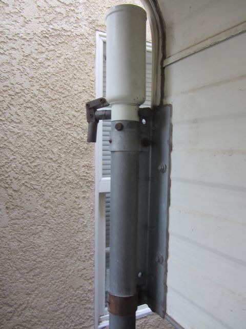 1986 Yugo GV - A close-up view of an outdoor weather instrument component, likely a rain gauge, attached to a building's exterior.
