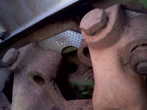 1989 Ford Bronco - Close-up view of heavily rusted metal parts and large bolts, suggesting mechanical components.