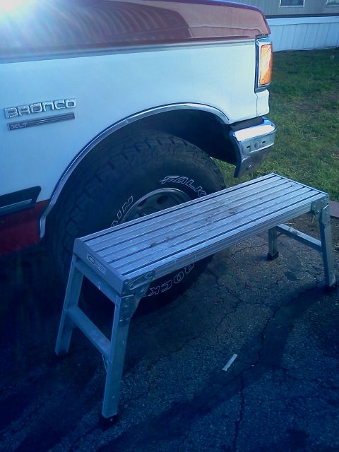 1989 Ford Bronco - A step stool is positioned in front of the rear wheel of a Ford Bronco.