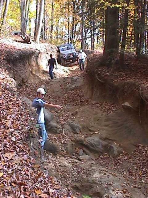 1996 Ford Bronco - Two people and a Jeep navigate a challenging off-road trail during autumn.