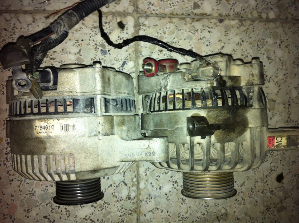 Two automotive alternators on a tiled floor.