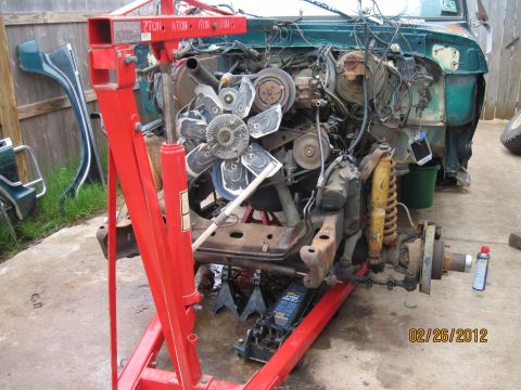 1979 Ford Bronco - Engine and chassis components are laid out for repair or restoration, supported by an engine hoist and jack stands.