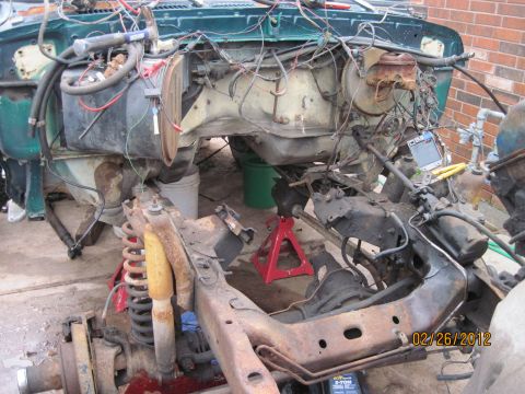 1979 Ford Bronco - The vehicle's chassis and engine bay are disassembled, revealing exposed wiring and suspension components, suggesting a project in progress.