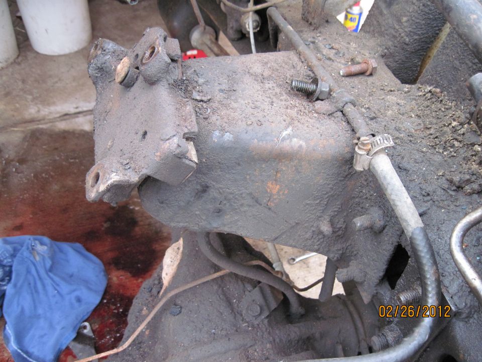 close-up of greasy steering gearbox with hoses and bolts
