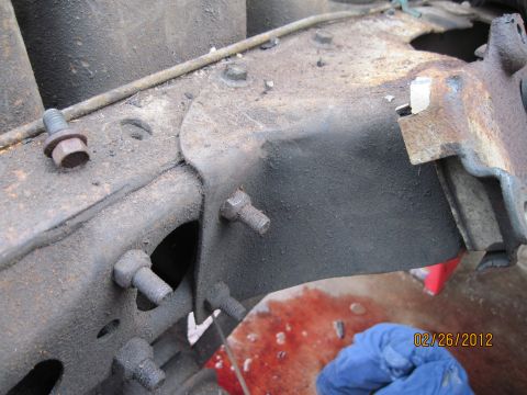1979 Ford Bronco - A close-up view of a vehicle's frame shows signs of wear and a spill of red fluid on the ground.