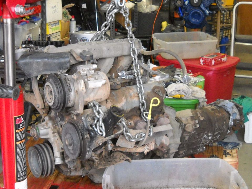 Engine and transmission assembly being hoisted by chains in a garage