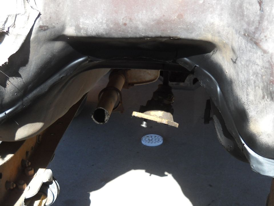 Underside view of vehicle exhaust pipe and suspension components. Supermotors.net logo visible
