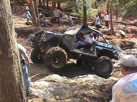 1996 Ford Bronco - A heavily modified Ford Bronco tackles a challenging off-road course with spectators watching.
