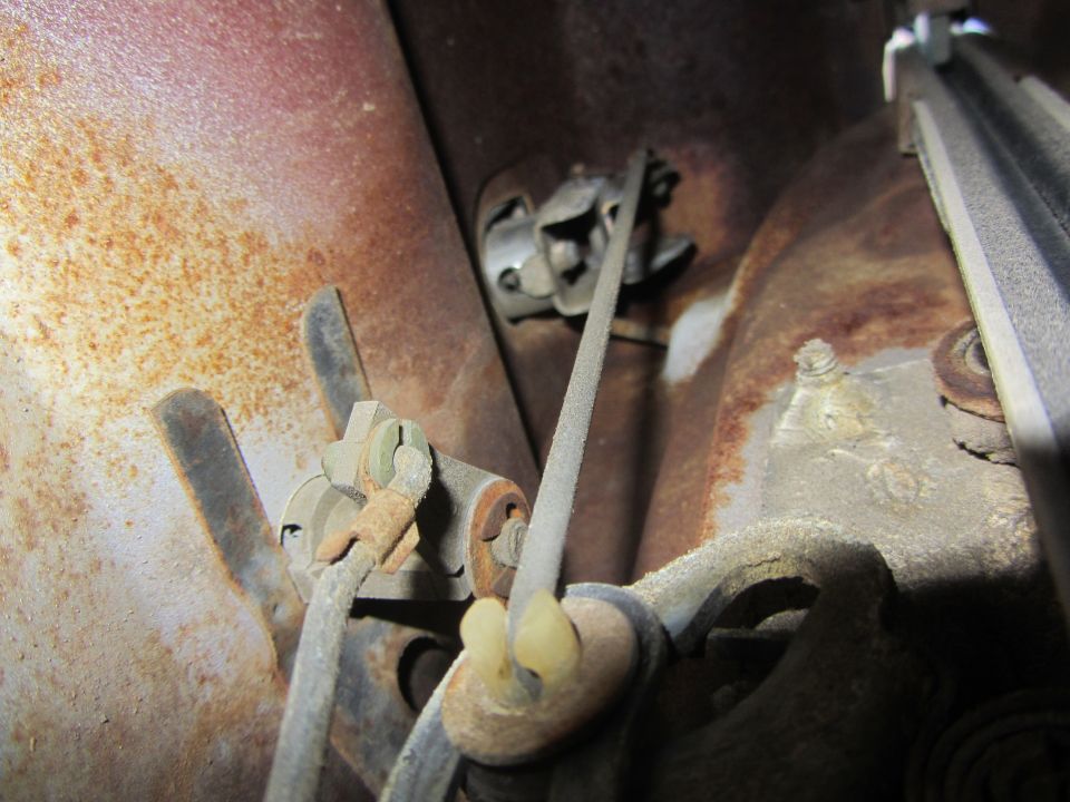Close-up of rusty door latch mechanism with cables and clips