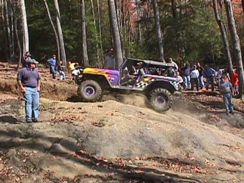 1996 Ford Bronco - A customized off-road vehicle navigates a challenging rocky incline with spectators watching.