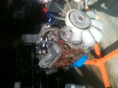 1988 Ford Bronco II - Engine assembly with a prominent fan, resting on an orange stand.