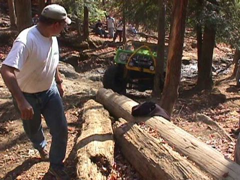 1996 Ford Bronco - An off-road vehicle navigates a challenging course of logs in a forest setting.