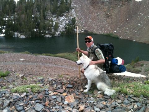 1988 Ford Bronco II - A man and his husky dog pose with backpacks beside a lake in a , mountainous landscape.