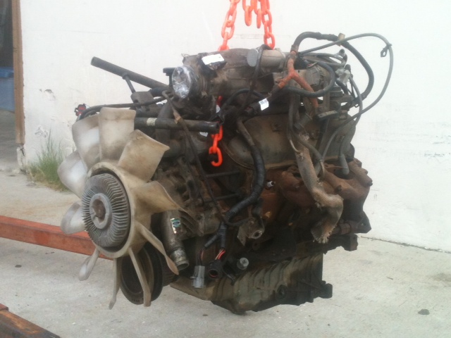 Engine assembly with fan and hoses, suspended by orange chains