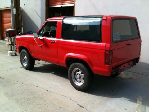 1988 Ford Bronco II - This red 1988 Ford Bronco II is parked in front of an open garage door.