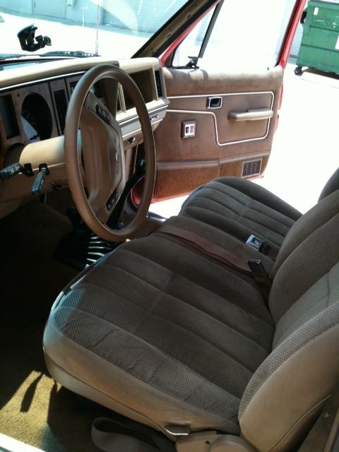 1988 Ford Bronco II - The interior of a vintage SUV features brown fabric seats and door panels, with a visible dashboard and steering wheel.