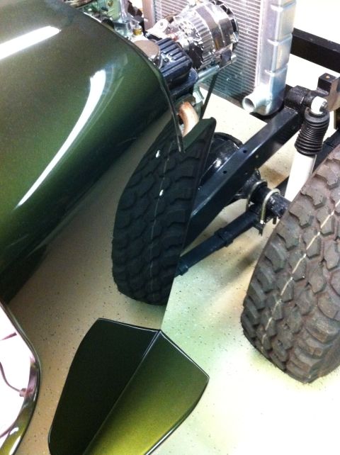 1948 Jeep Wrangler - Close-up of a green vehicle's fender and tire, showing mechanical parts and a metallic finish.