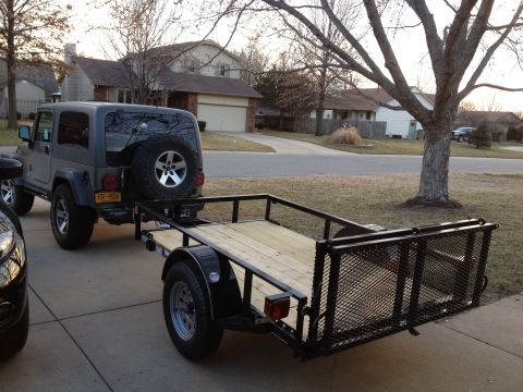 2005 Jeep Wrangler - A 2005 Jeep Wrangler is parked, hitched to a utility trailer on a driveway.