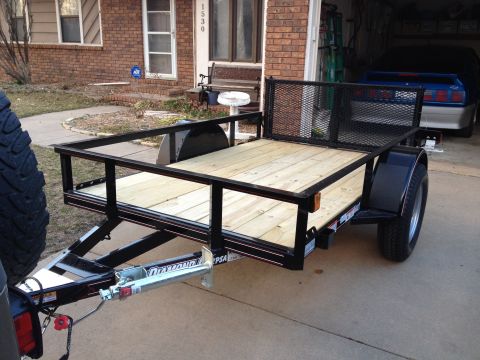 2005 Jeep Wrangler - A utility trailer is parked in front of a house, with a blue car visible in the open garage.