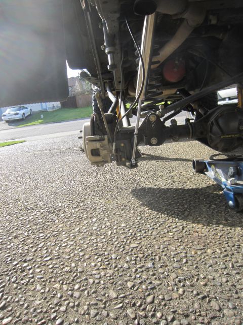 2008 Jeep Wrangler - The rear suspension and axle assembly of a vehicle are shown, with a hydraulic jack positioned nearby.
