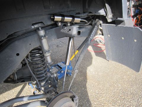 2008 Jeep Wrangler - The rear suspension of a Jeep Wrangler shows an Antirock sway bar and a shock absorber, with a blue jack supporting the vehicle.