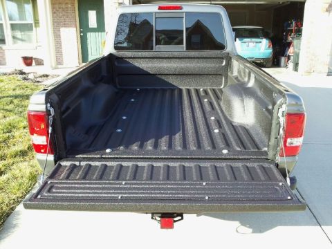 2011 Ford Ranger - The spray-in liner of a 2011 Ford Ranger truck bed is shown from the rear, with another vehicle visible in the background garage.