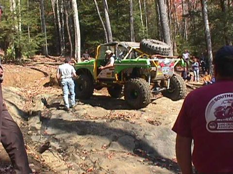 1996 Ford Bronco - An off-road vehicle navigates a challenging rocky terrain in a wooded area.