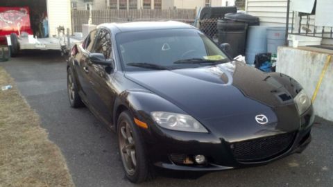 1987 Mazda RX-7 - Black Mazda RX-8 parked in a driveway with a trailer in the background.