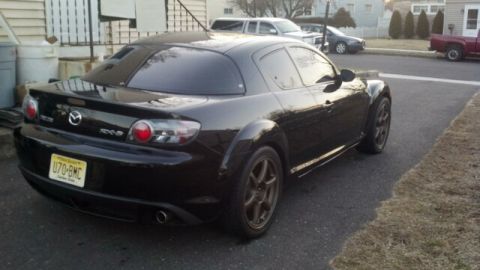 1987 Mazda RX-7 - Rear view of a black Mazda RX-8 with tinted windows and aftermarket wheels.