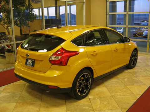 2012 Ford Focus - A yellow 2012 Ford Focus hatchback is parked indoors, showing its rear and side profile.