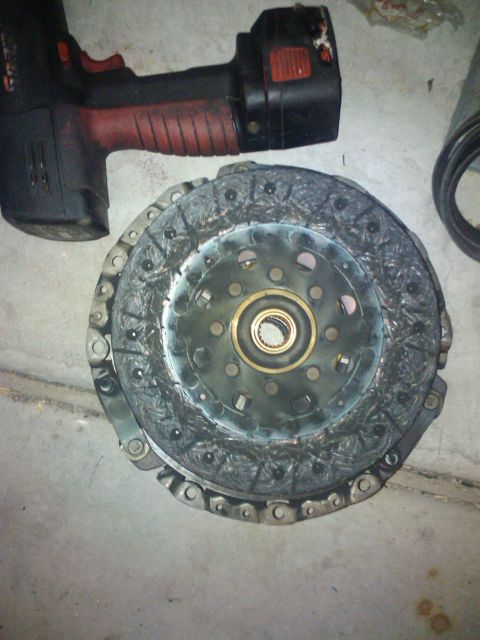 2003 Hyundai Tiburon - A worn clutch disc assembly is shown with a power tool nearby, indicating automotive repair or maintenance.