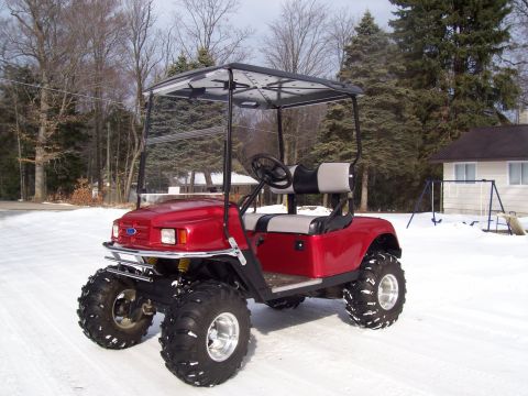 1978 Ford F-150 - This red golf cart is equipped with oversized tires, suggesting it is designed for off-road or rough terrain use, as seen here in a snowy e…