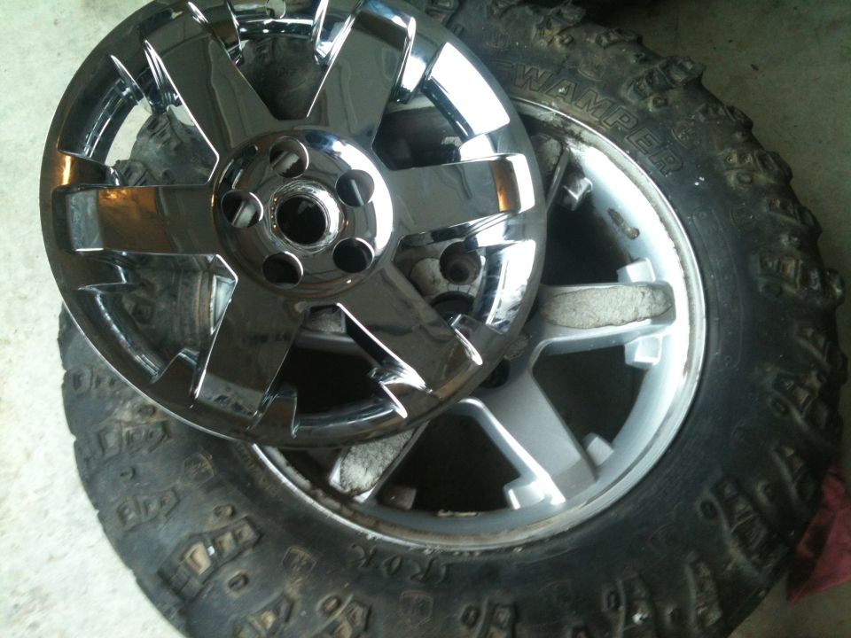 Chrome wheel sitting on top of a knobby tire. Text on tire says 'WAMP' and 'SUPERMOTORS.NET' is visible at the bottom