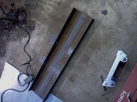 1989 Ford Bronco - A metal winch mount lies on a concrete floor next to a power cord and metal sheeting.