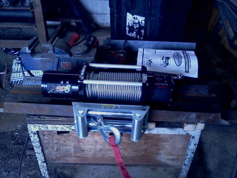 1989 Ford Bronco - A winch and its mounting hardware are displayed, with instructions visible in the background.