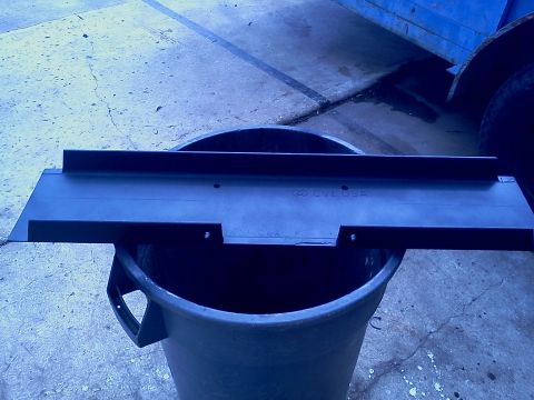 1989 Ford Bronco - A black metal part, possibly a winch mount, is placed on a bucket.