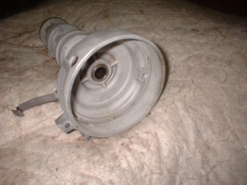 1969 Mercury Cyclone - A close-up view of a metal automotive distributor part resting on a textured surface.