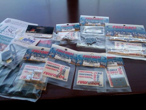 1986 Ford Bronco - Various RC car parts are laid out on a table, some in original packaging.