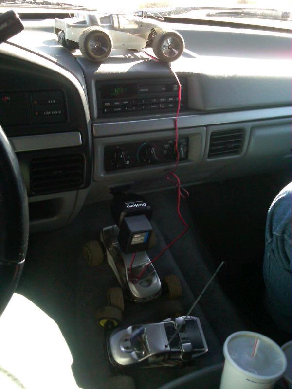 Dashboard interior with two remote control cars, one on top of the other, and a cup holder