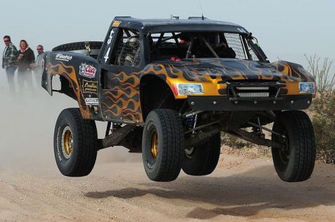 1986 Ford Bronco - This off-road racing truck, adorned with flame decals, is captured mid-air during a race.