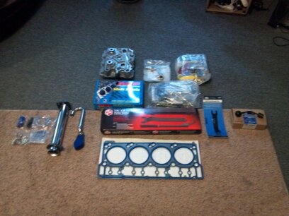1993 Ford F-150 - Collection of engine parts and tools, including a gasket and cylinder head, arranged on a carpet.