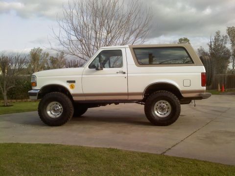 1996 Ford Bronco - This lifted 1996 Ford Bronco is shown from the side, its off-road tires and two-tone paint scheme.