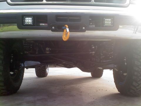 1996 Ford Bronco - Close-up of the front suspension and bumper assembly, aftermarket LED lights and a prominent tow hook.