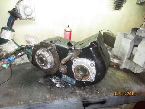 1979 Ford Bronco - A black NP205 transfer case sits on a cluttered workbench next to a propane torch and spray can.