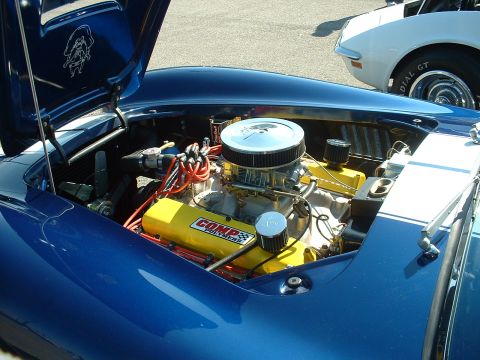 1995 Ford Crown Victoria - The engine bay of a blue sports car is visible, with a white car parked nearby.
