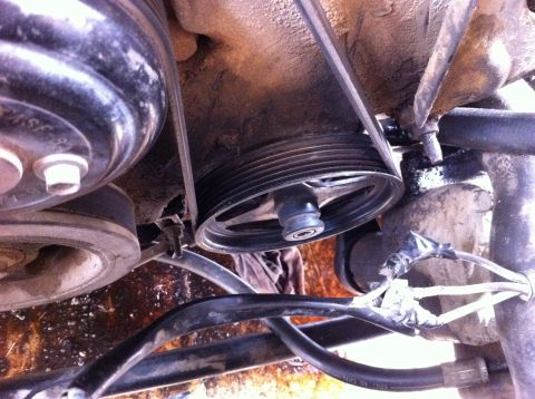 1998 Ford Crown Victoria - Close-up view of engine pulleys and belts, showing signs of wear and fluid leaks.
