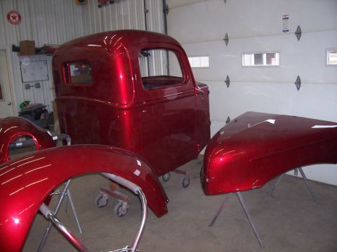 1978 Ford F-150 - Classic truck cab and fenders painted in a metallic red finish are displayed in a workshop.